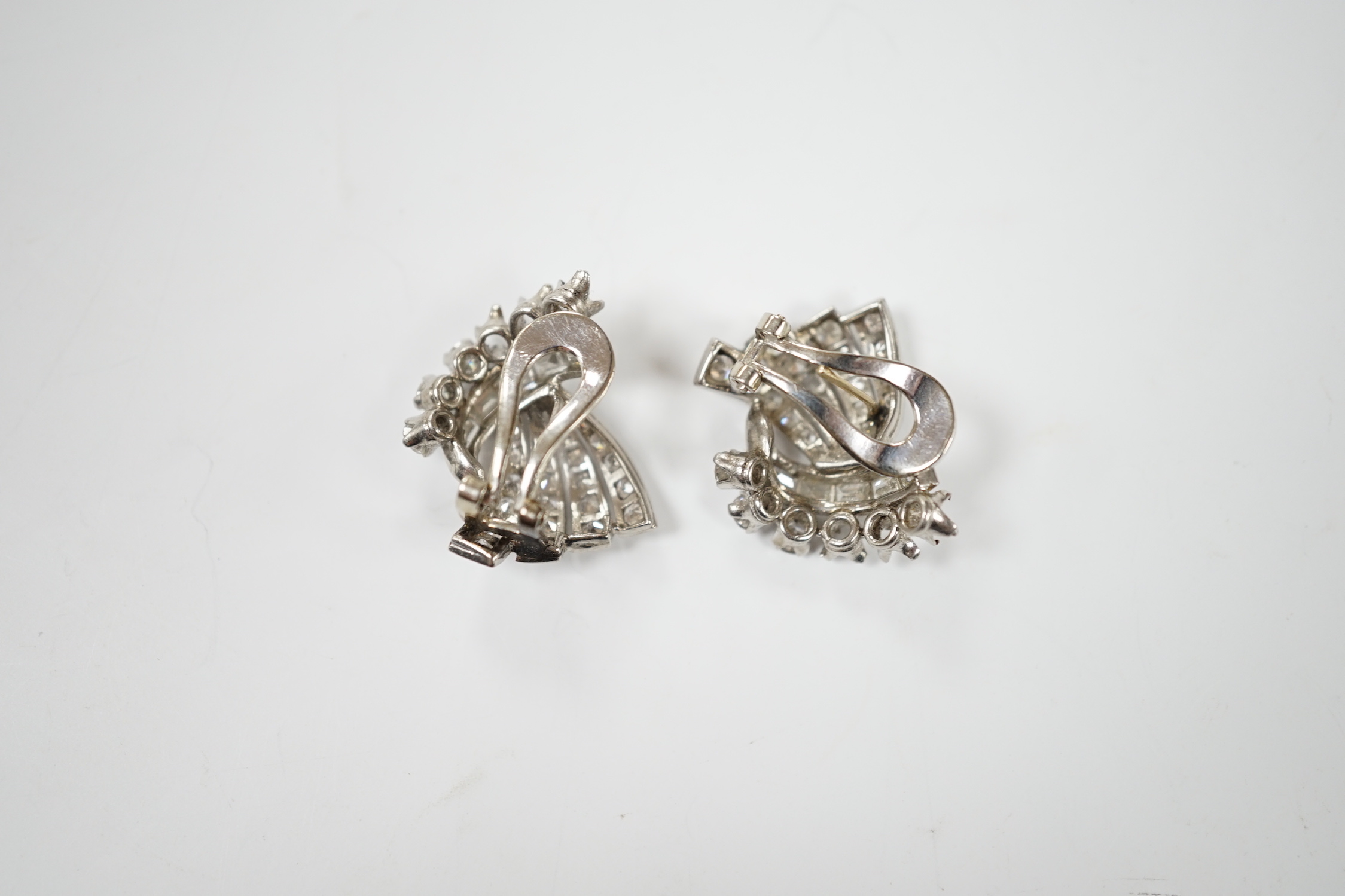 A pair of white metal, round and baguette cut diamond cluster set fan shaped earrings, 20mm, gross weight 10.7 grams (three stones missing from each).